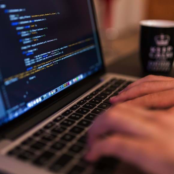 Developer working at a laptop on the code for an IT system integration.