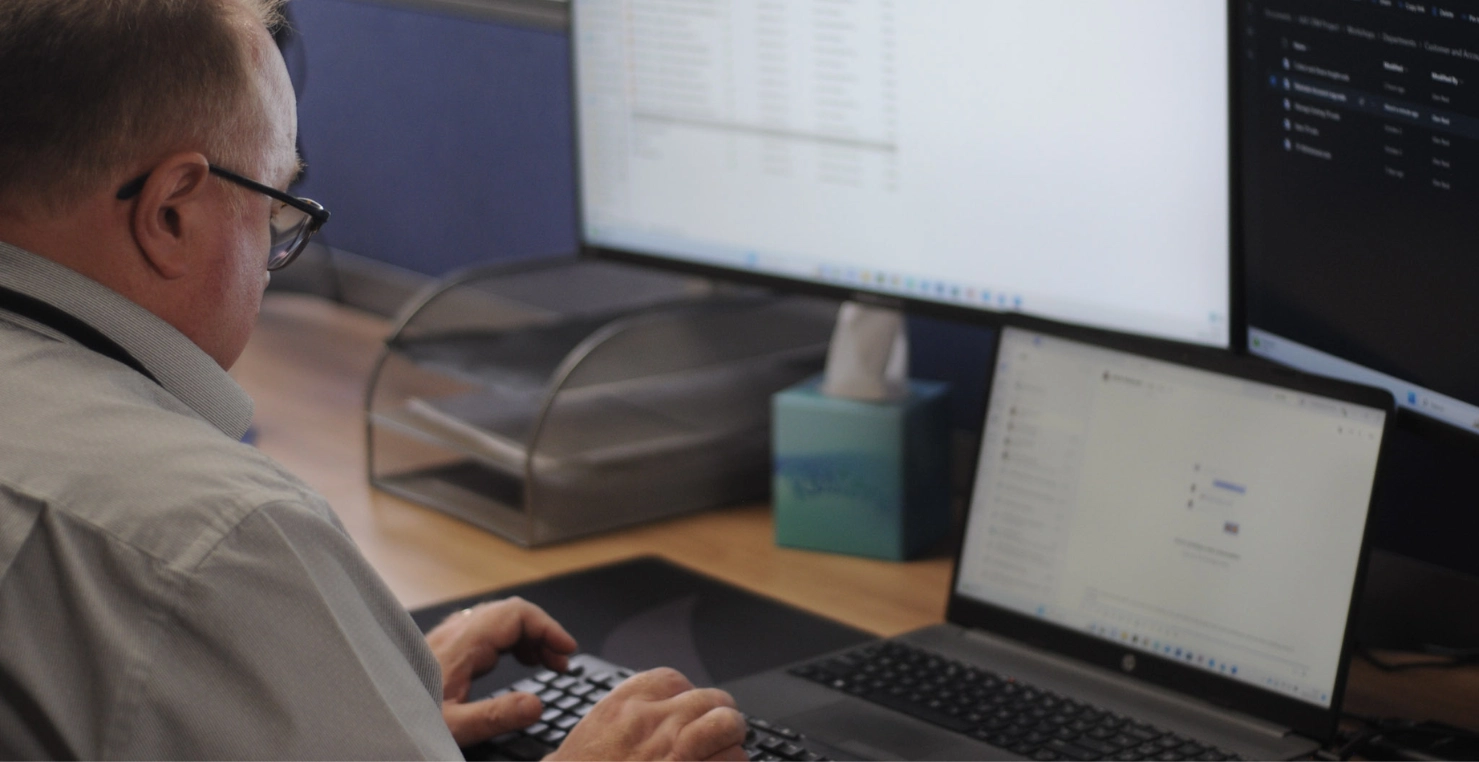 A PSP developer typing on keyboard with laptop and monitors in front of him.