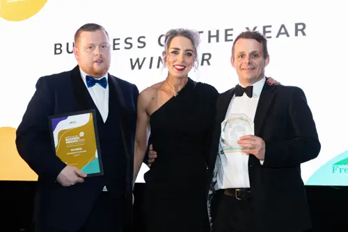 Two men and lady holding a the business of the year award